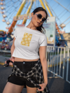 Woman wearing a white t-shirt with a yellow design and black shorts at an amusement park.